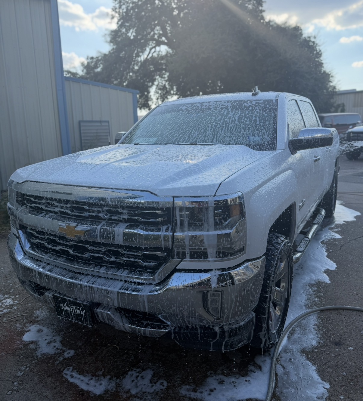White Chevrolet truck covered in foam during an exterior detail